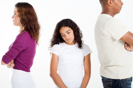 Unhappy girl standing between divorcing father and mother